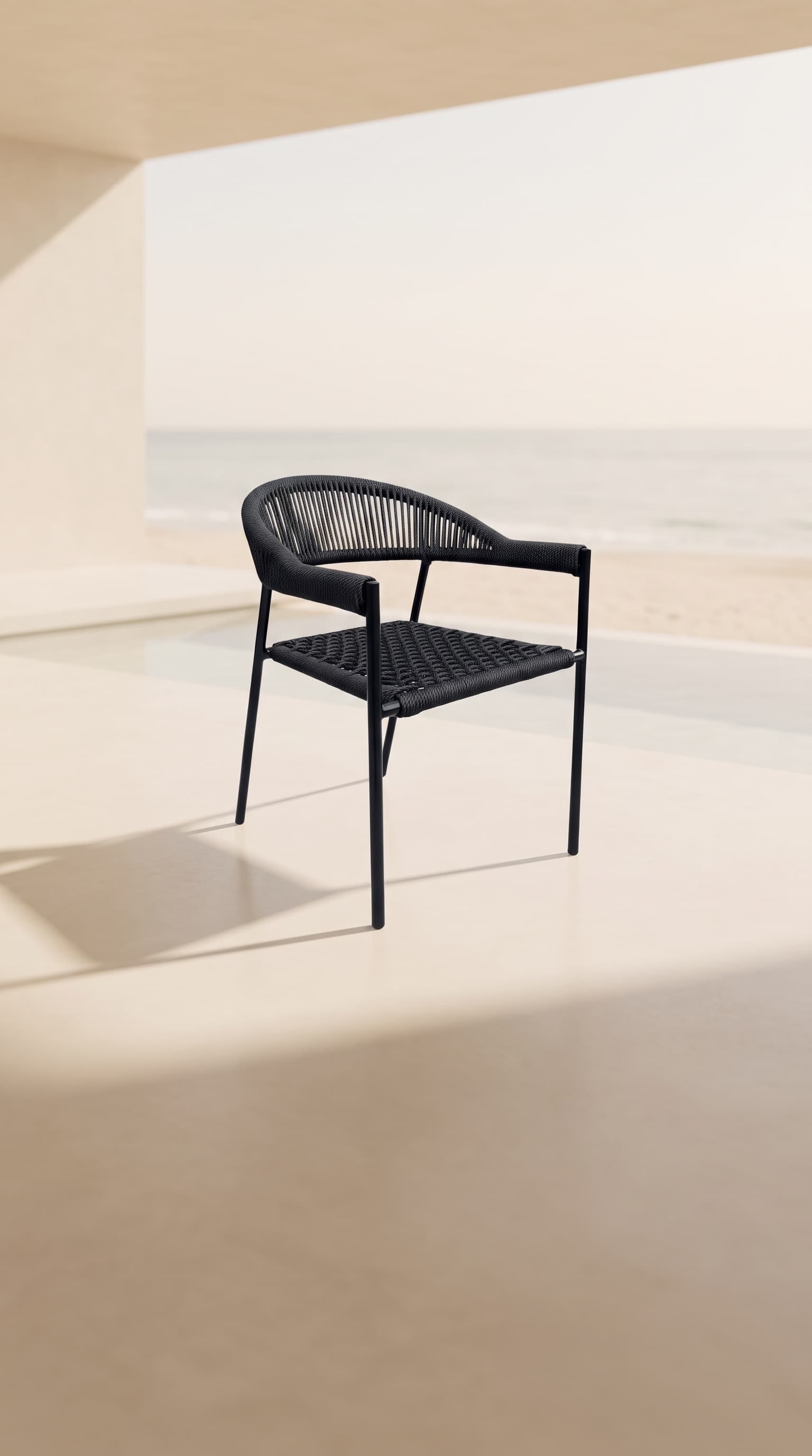 Silla tejida Capri negra en la terraza de una suite, frente a la alberca y el mar